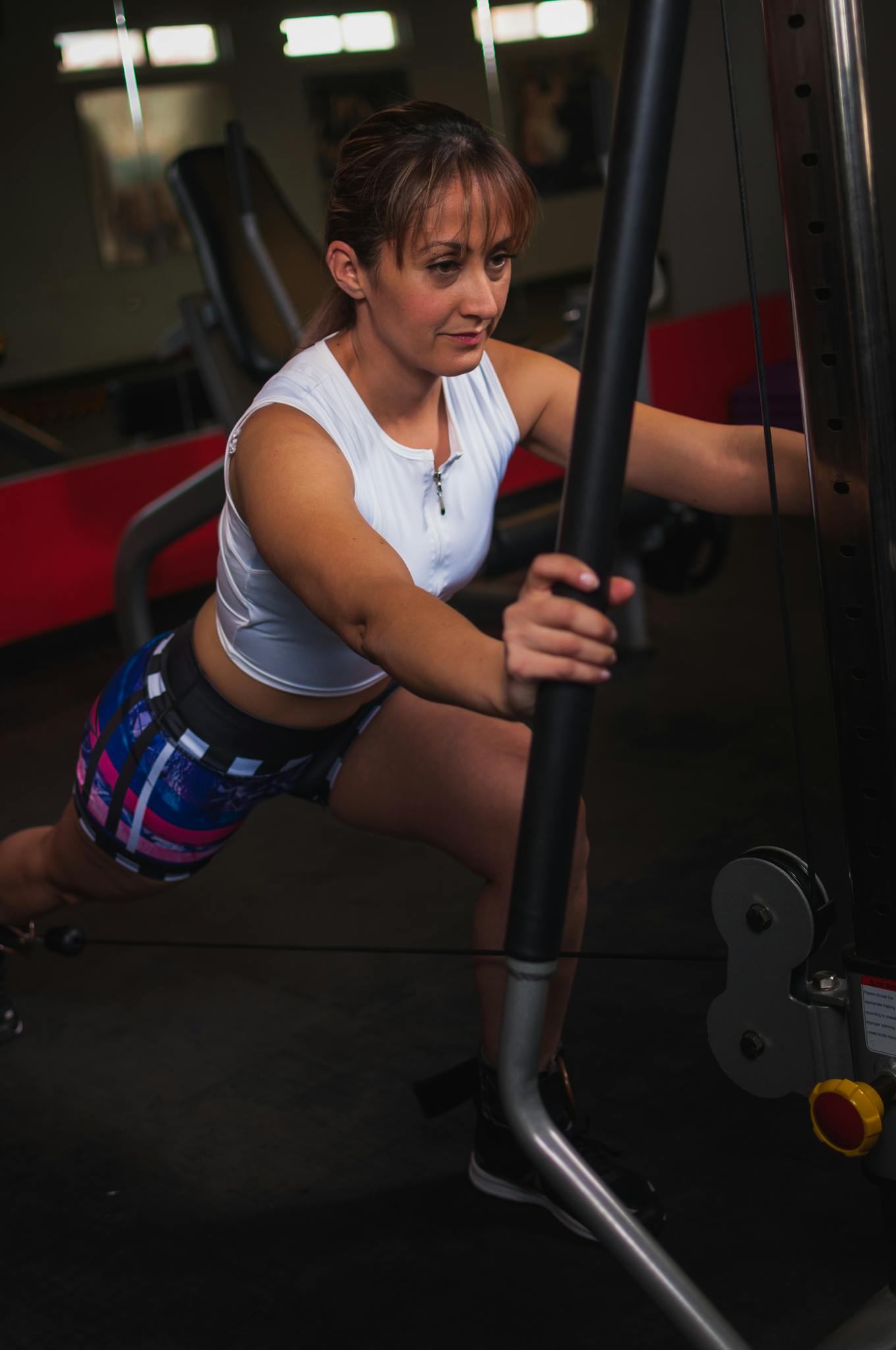 Adult woman working out with exercise equipment in a gym setting, focused on fitness and strength.