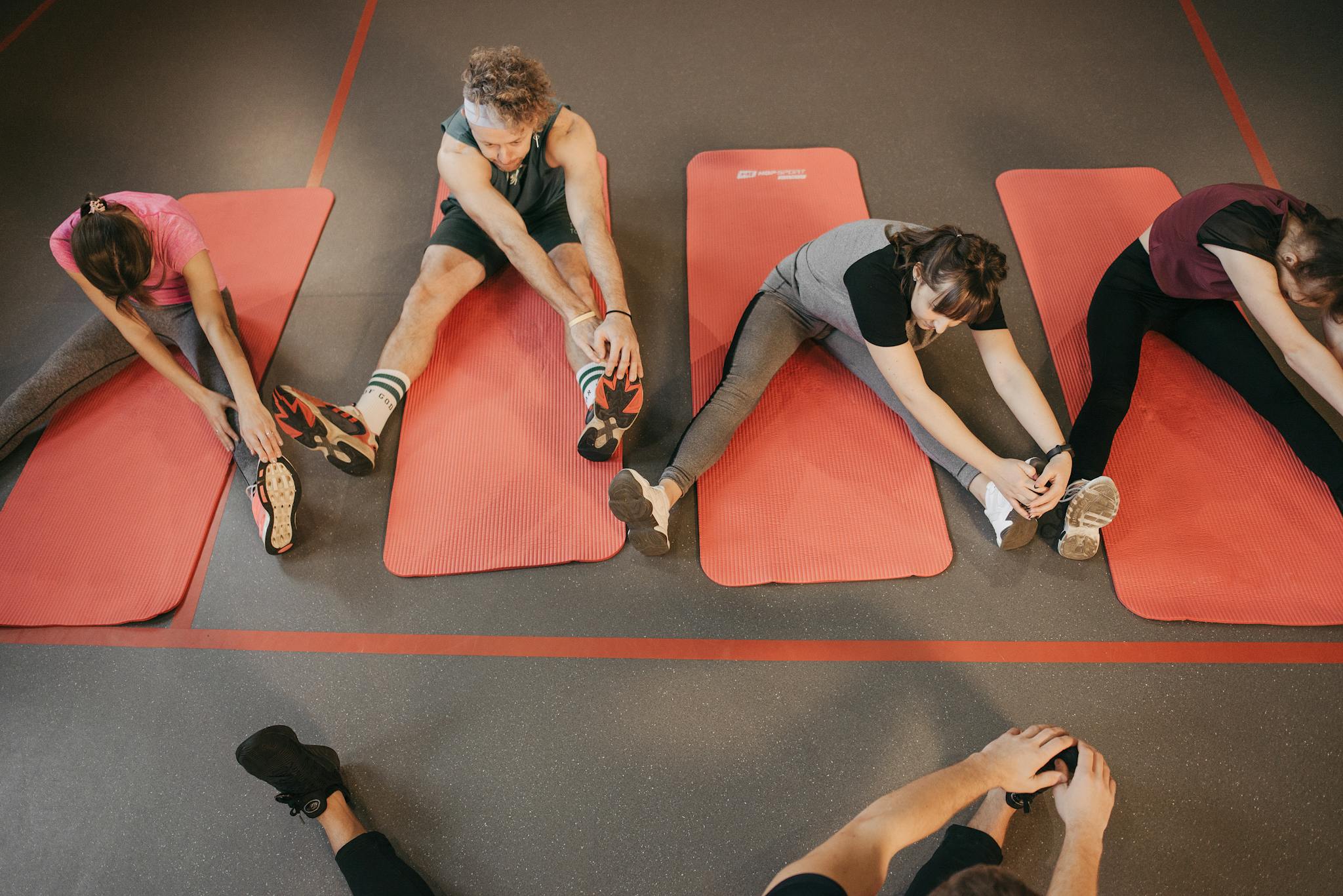 Yoga instructor with pink hair assisting a male student in a studio session, focused on wellness.