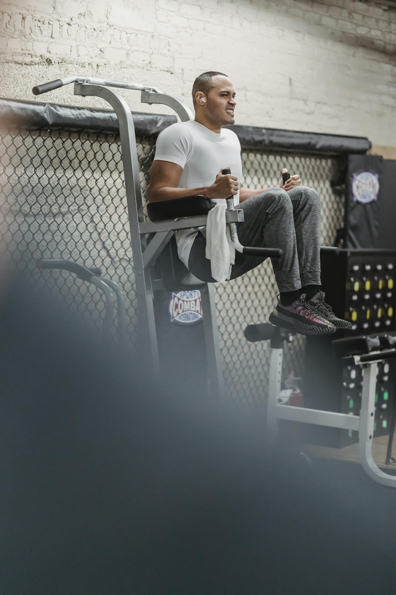 Full body of male athlete in sportswear doing knee to chest exercise on sport equipment during intense workout