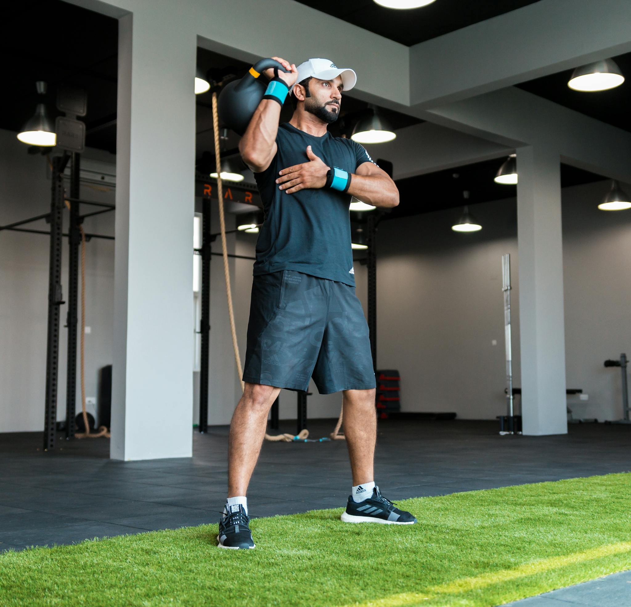 Man in activewear lifting a kettlebell indoors at a modern fitness center.